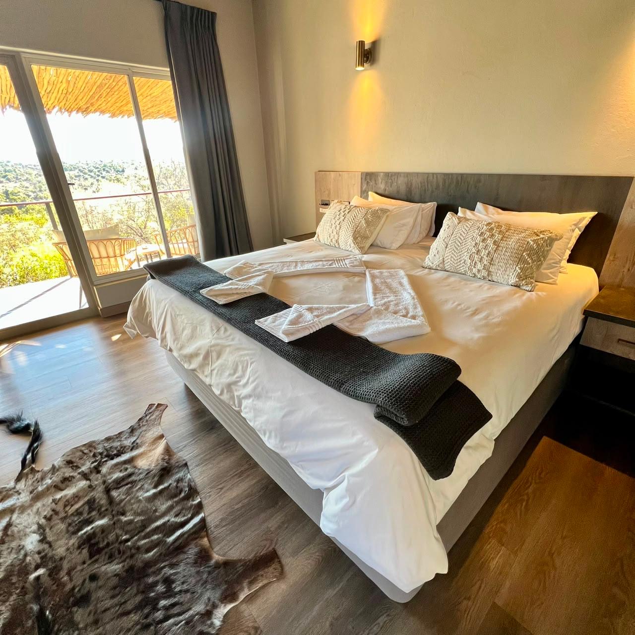 King-size bedroom with sliding doors opening onto a private balcony at Sithrah Lodge