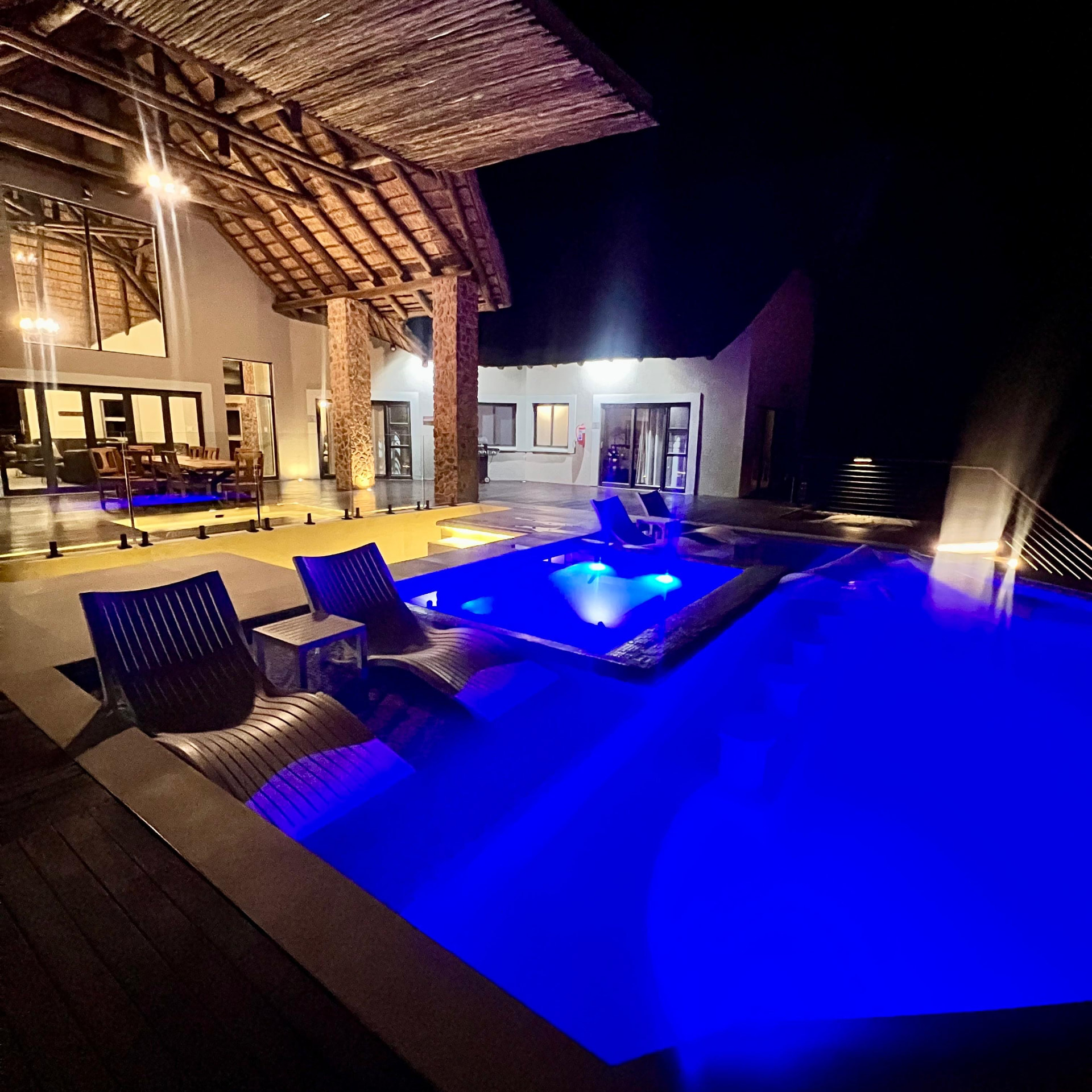 Tebuah Private Lodge lit at night with the pool and jacuzzi glowing blue