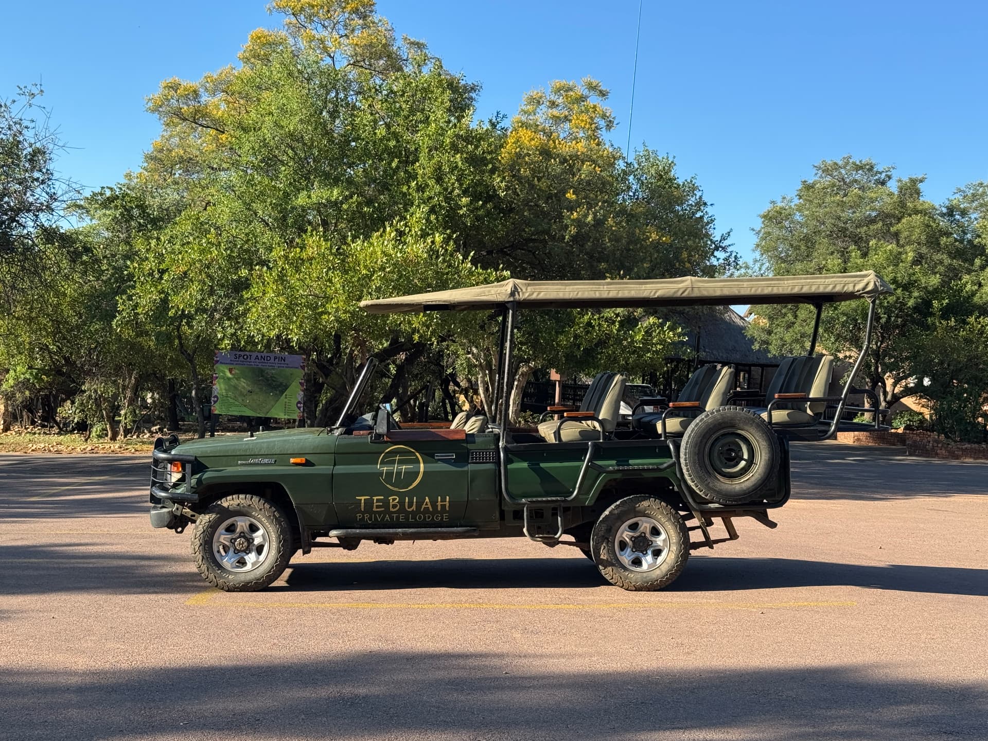 Tebuah Private Lodge branded open game viewing vehicle parked under the trees in Mabalingwe Nature Reserve