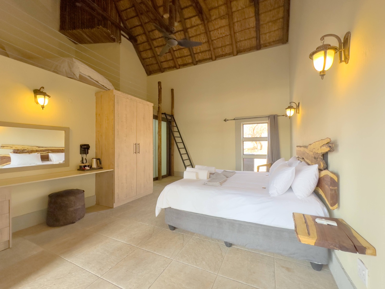 En-suite bedroom with king bed, live-edge headboard and high thatched ceiling at Tebuah Private Lodge