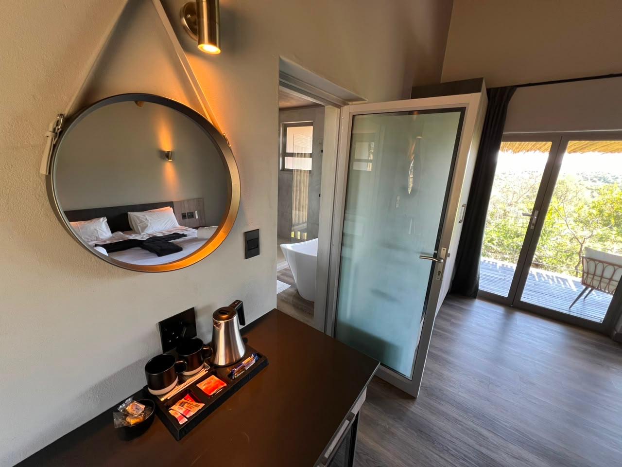 Suite entrance with coffee tray, round mirror and bushveld-facing doors at Sithrah Lodge