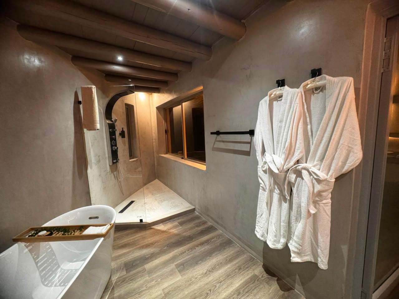 Freestanding bath, walk-in rain shower and robes in a Sithrah Lodge en-suite bathroom