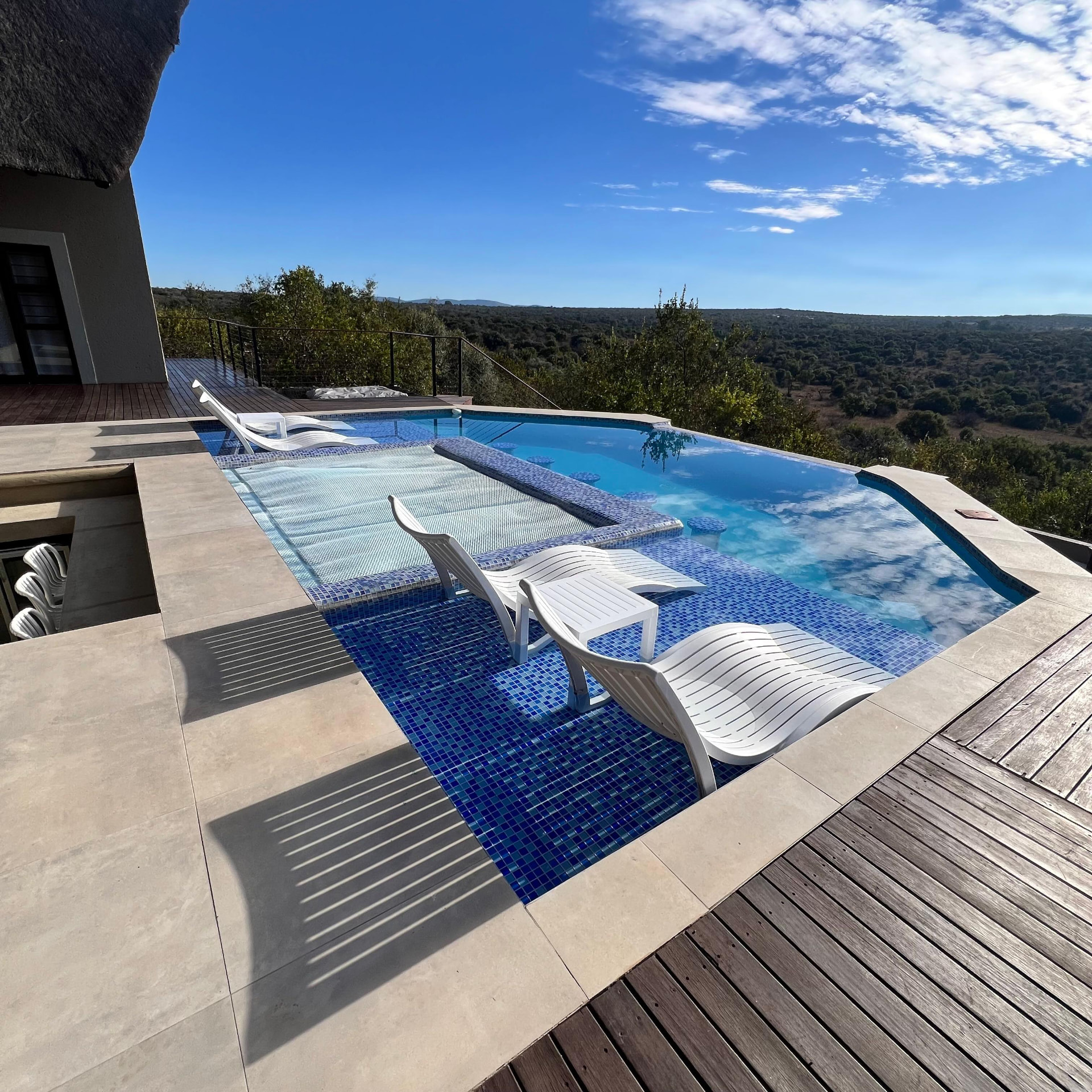 Sun loungers on the mosaic pool shelf at Tebuah Private Lodge in the afternoon light