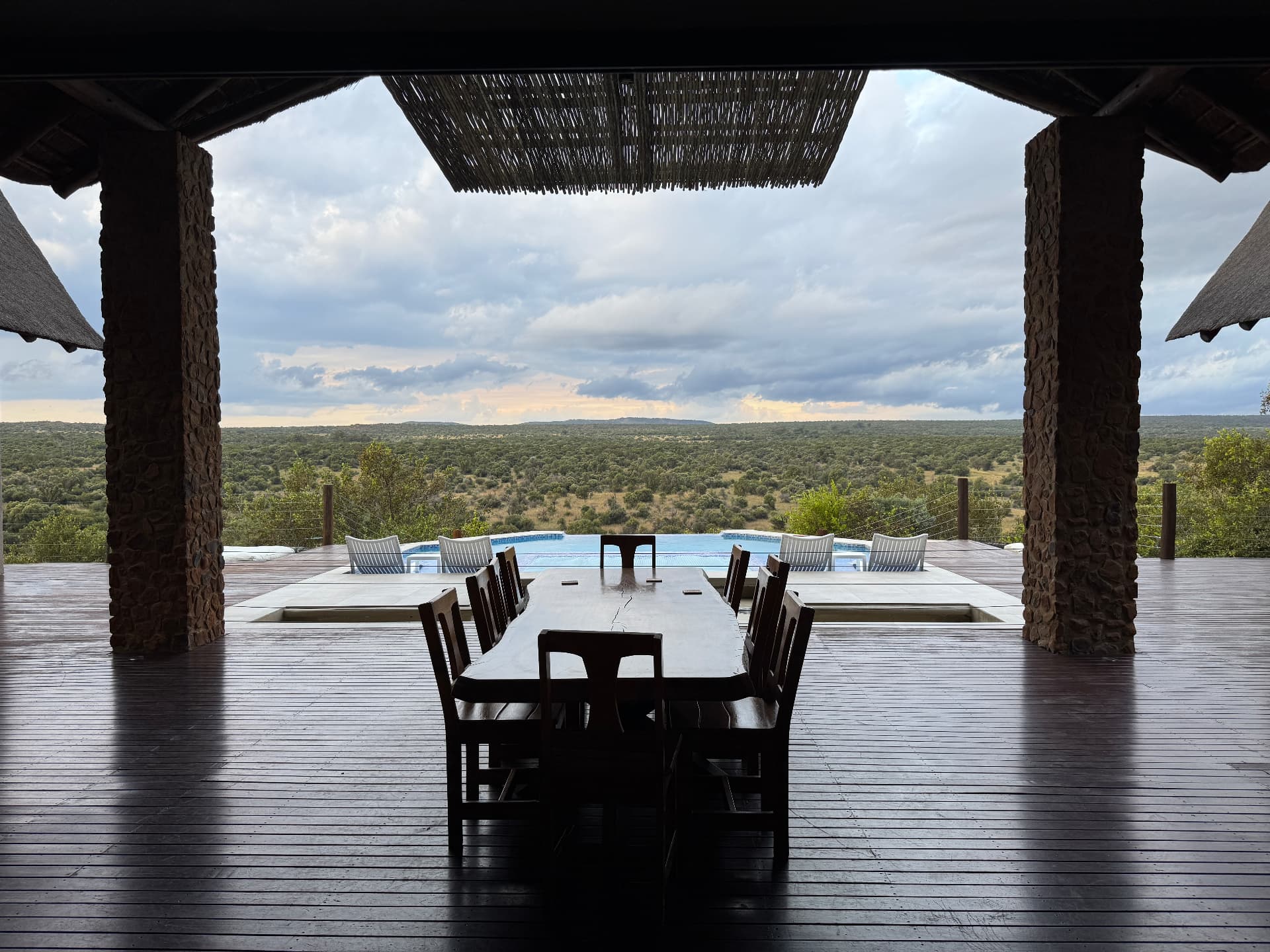 Long dining table on the covered deck at Tebuah Private Lodge looking past the pool over the Waterberg