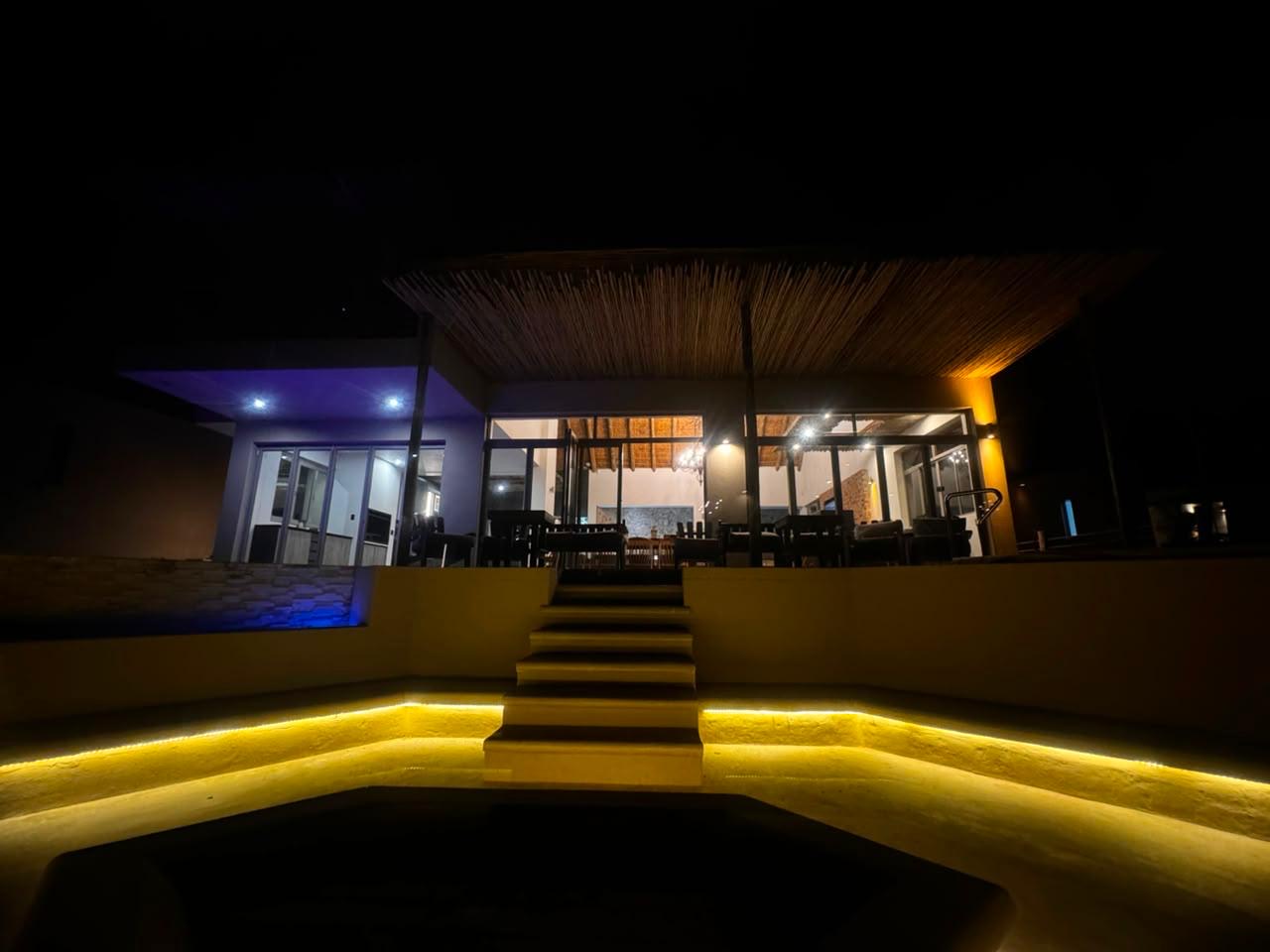 Lit patio, pool and entertaining area at Sithrah Private Lodge after dark