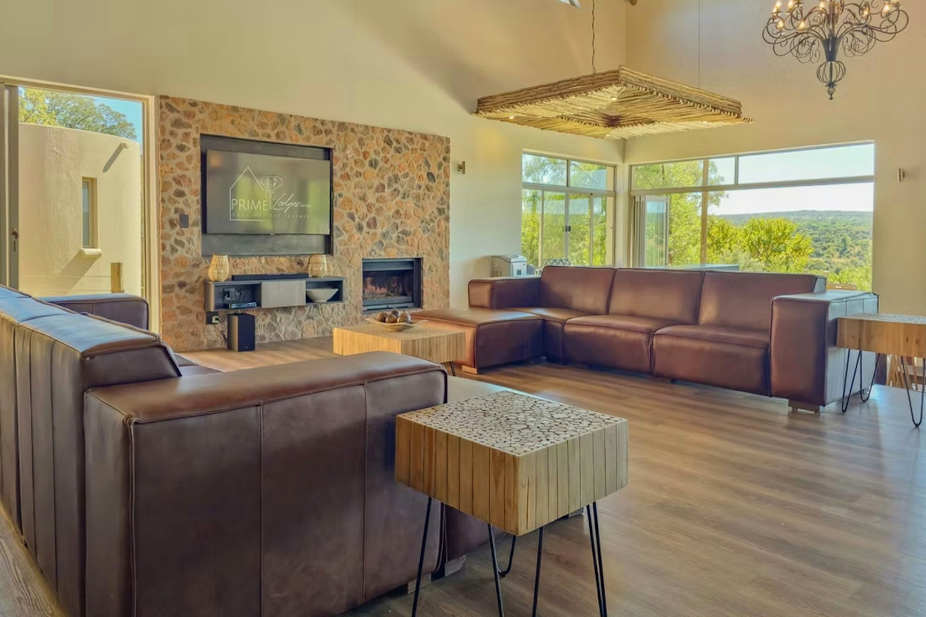 Lounge with leather couches and a stone fireplace under a high thatched roof at Sithrah Lodge